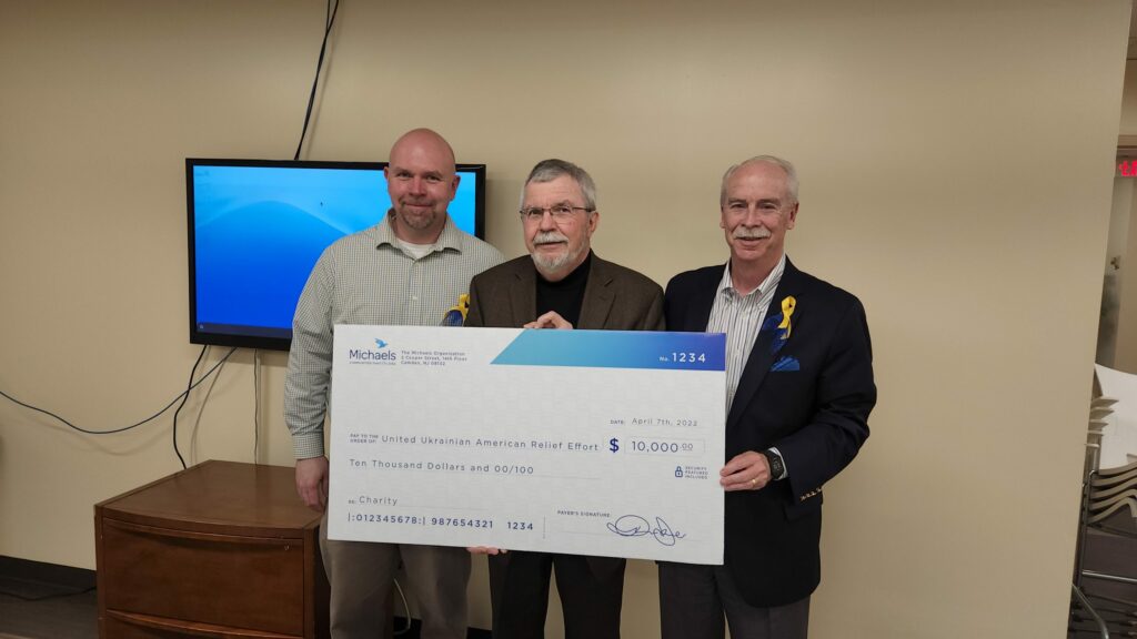 three men posing with large check